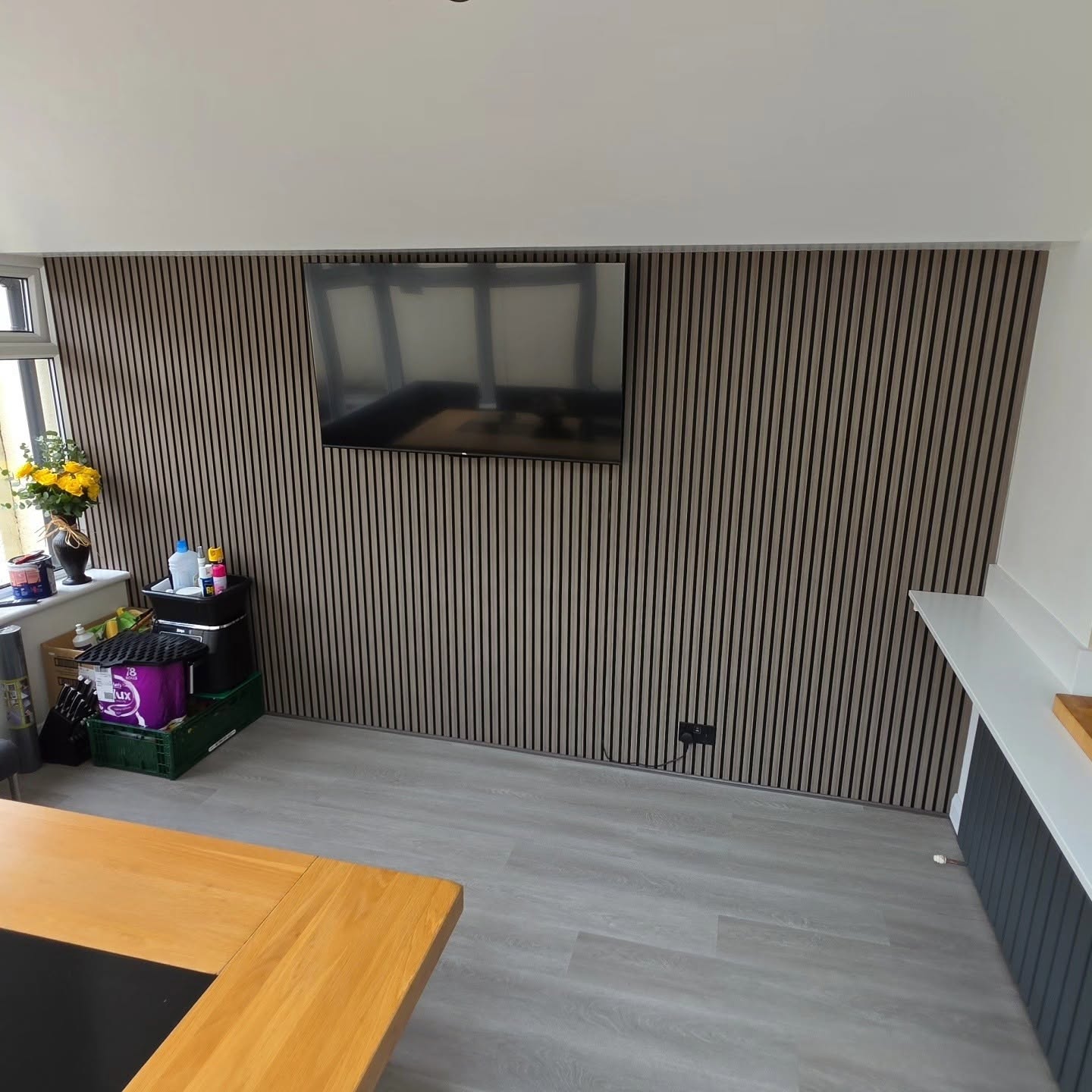 Open-plan living space with bespoke slat wall panelling and wall-mounted media wall