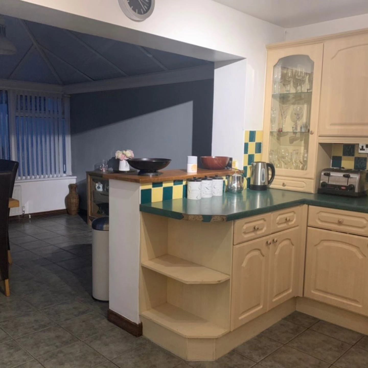 Dated kitchen with peninsula breakfast bar and green worktops before renovation