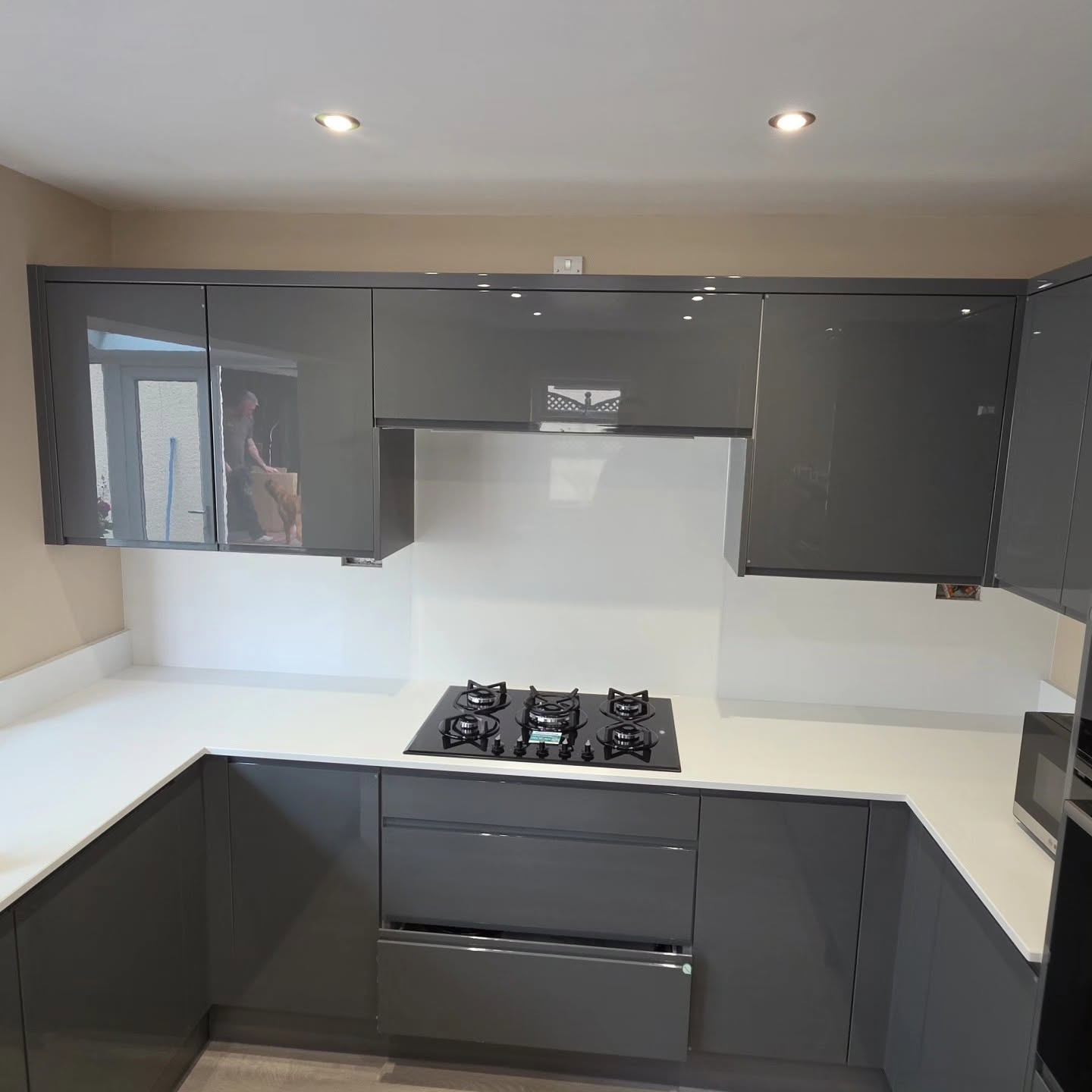 Modern grey gloss kitchen cabinetry with gas hob and white splashback