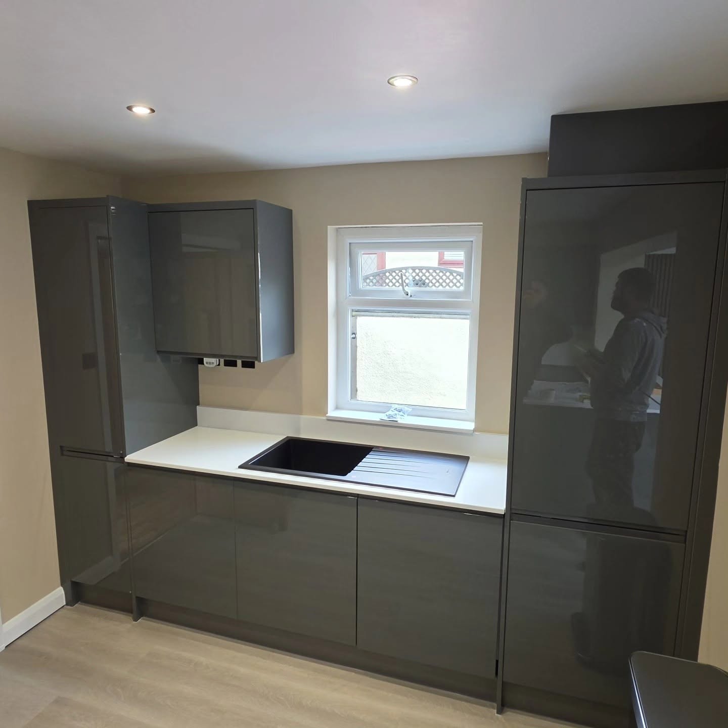 Modern kitchen sink run with black composite sink and grey oak LVT flooring