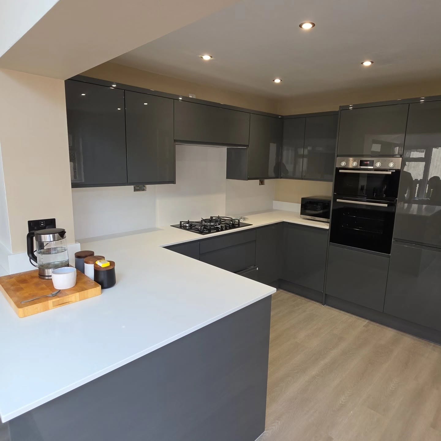 Grey gloss U-shaped Wren kitchen with white worktops, gas hob and integrated Bosch double oven
