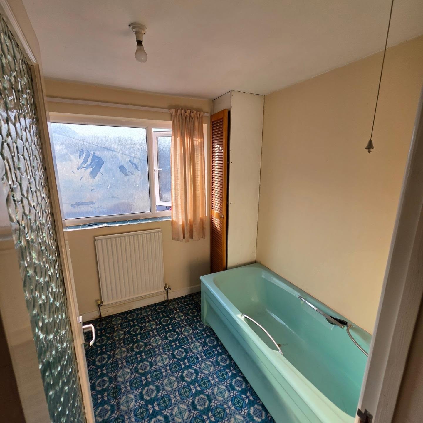 Before: original 1970s bathroom with turquoise bath and patterned carpet