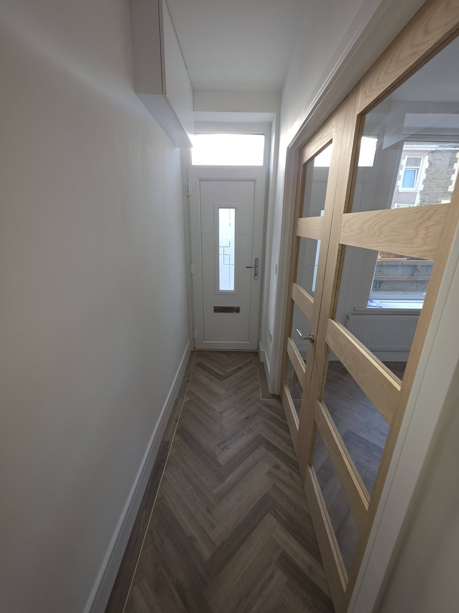 Hallway with oak glazed internal doors and herringbone LVT leading to the new front door