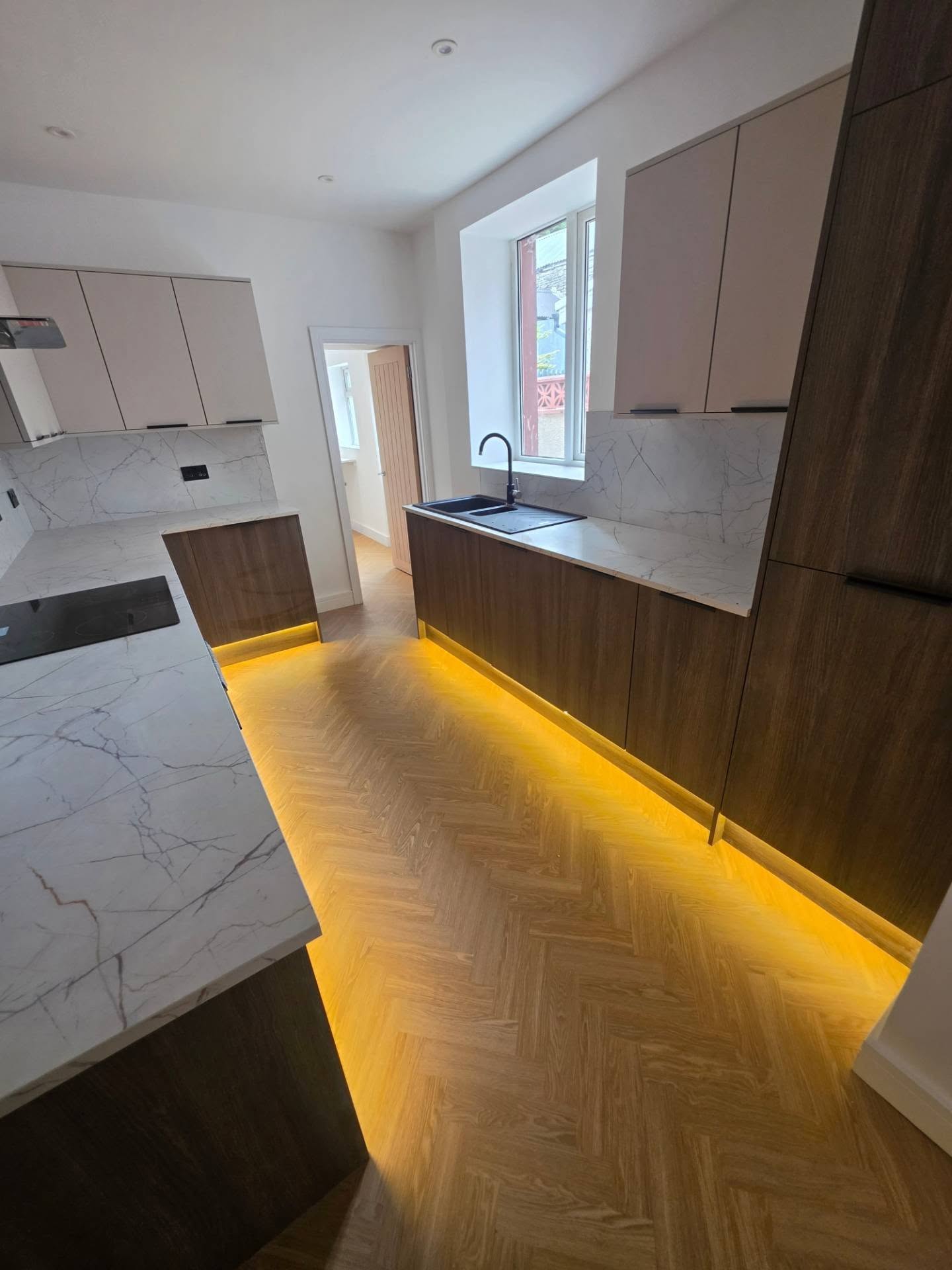 White marble-effect worktops and walnut units with LED plinth lighting throughout