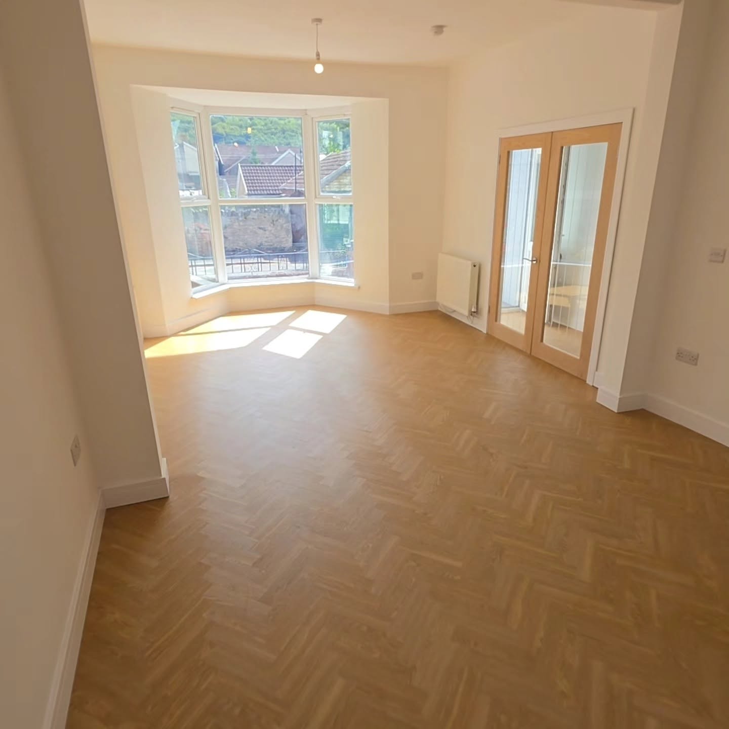 Renovated lounge in the Llanbradach terraced house with bay window, oak glazed double doors and herringbone flooring