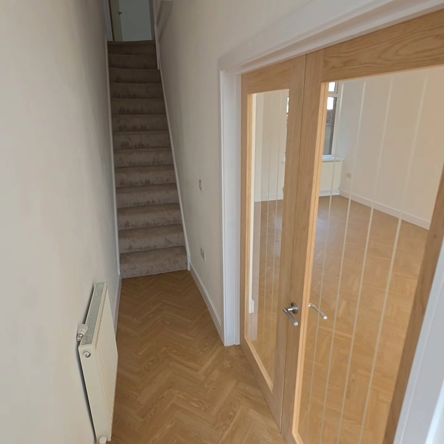 Renovated hallway with new stair carpet, oak glazed doors and radiator