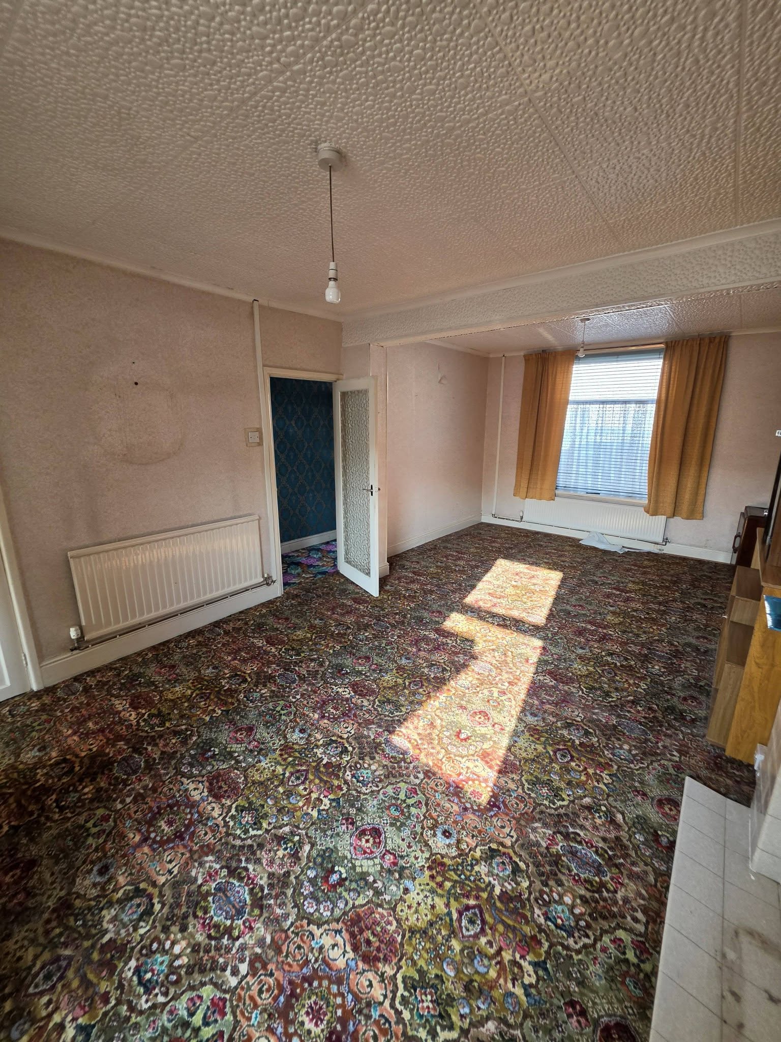 Before: tired lounge with patterned carpet and textured ceiling