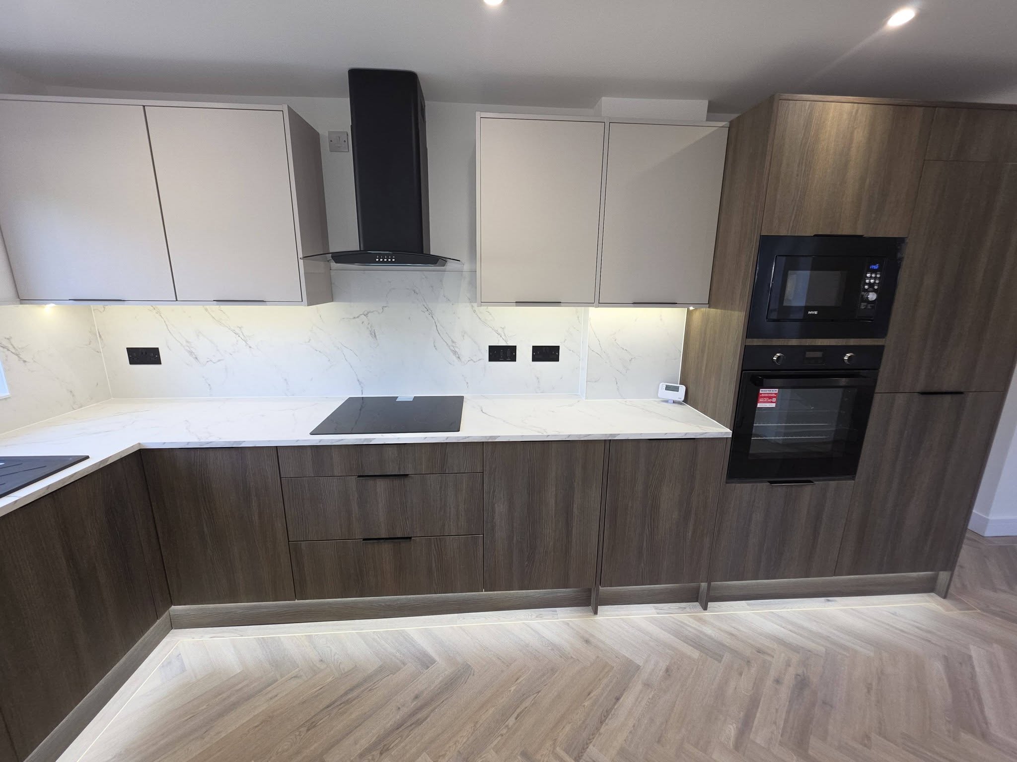 New kitchen with marble-effect worktops and splashback, black chimney extractor, induction hob and integrated oven and microwave